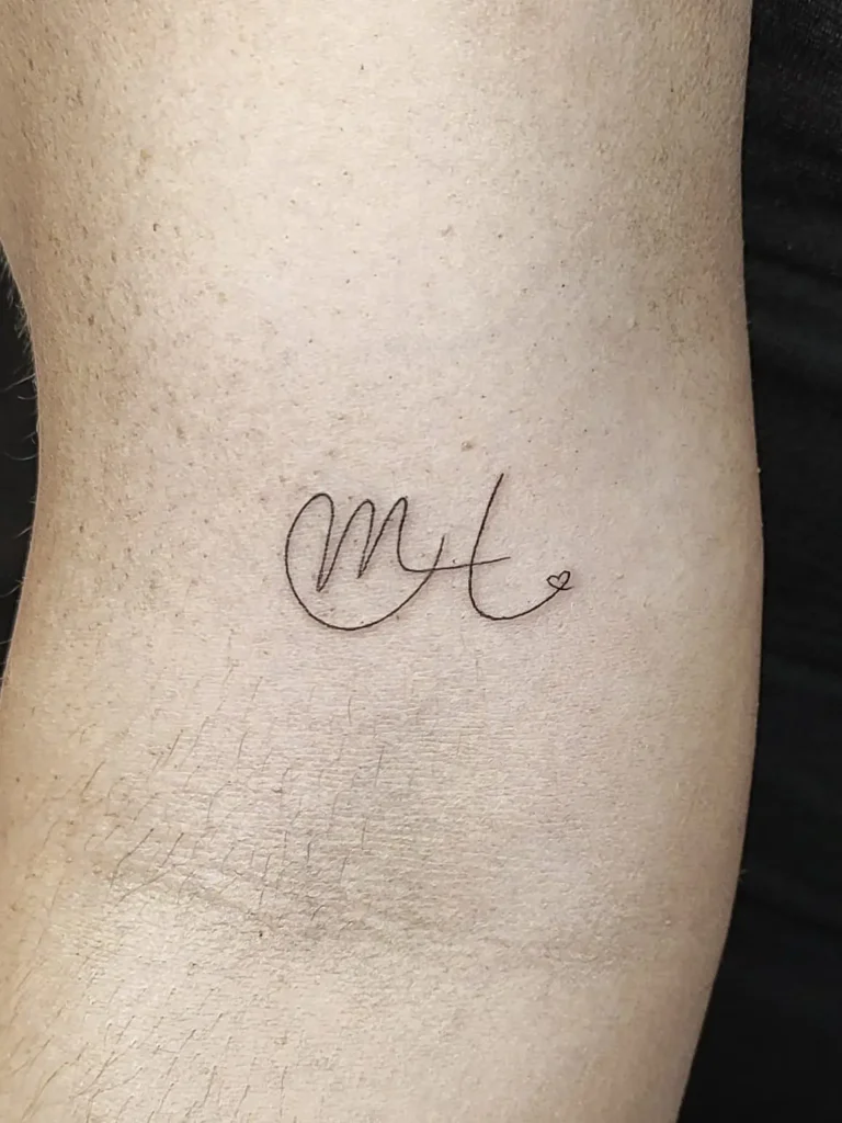 Tatuaje de dos iniciales enlazadas entre si en el brazo