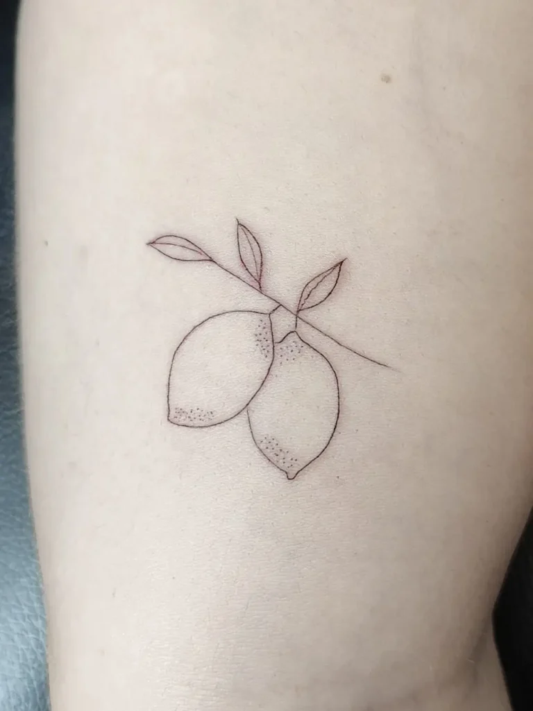 Tatuaje minimalista de dos limones en una rama en el brazo