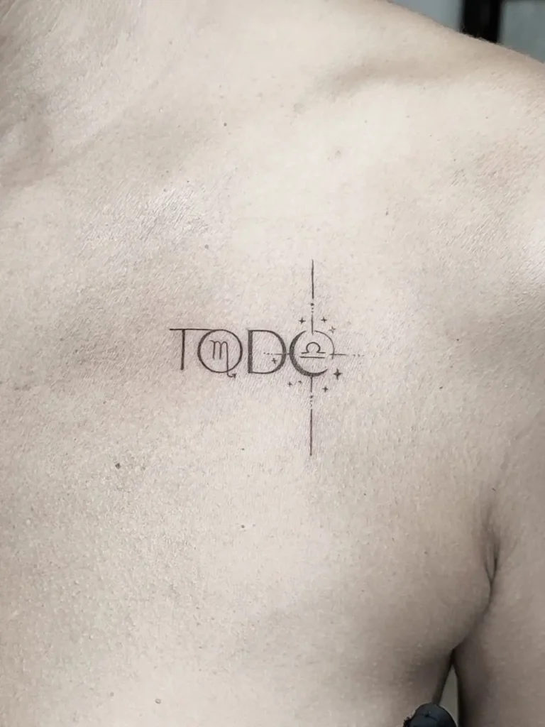 Tatuaje palabra todo con símbolo del zodíaco realizado en el pecho