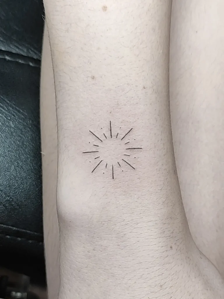 Tatuaje sol lineal minimalista realizado en la muñeca